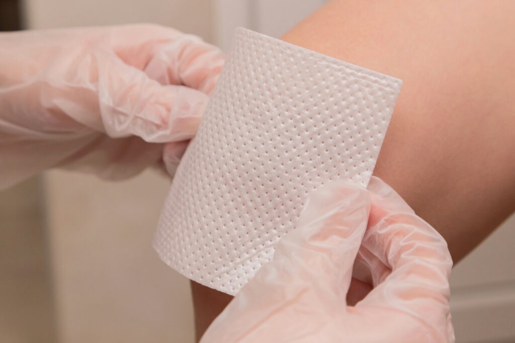 A nurse applies a bandage to a patients knee.