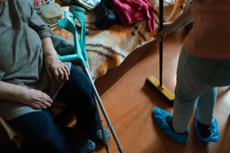 Caregiver helps an elderly woman with cleaning tasks, showcasing home care support